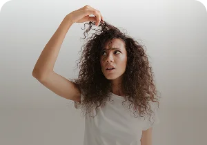 Woman with curly hair examining a strand – hair loss and alopecia